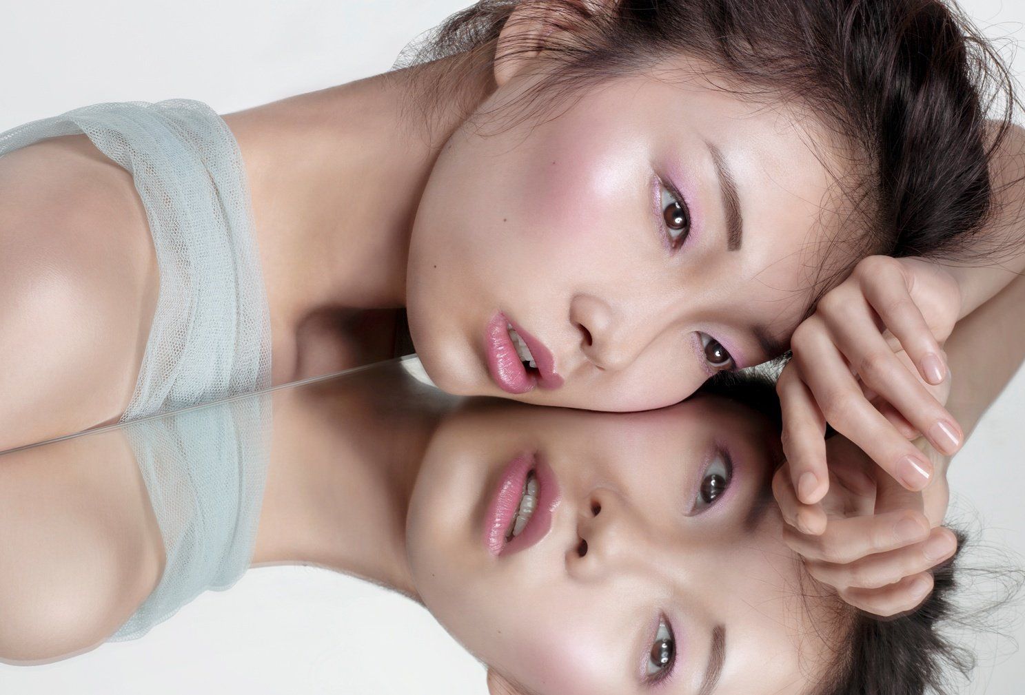 Model with dewy skin reflected in a mirror